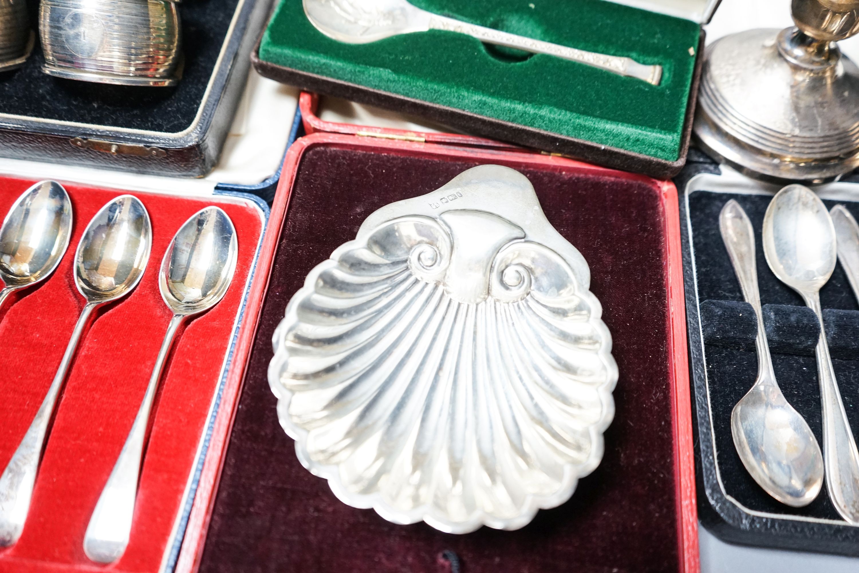 A cased pair of four 1920's silver napkin rings, four other cased items including butter shell and a pair of silver mounted dwarf candlesticks.